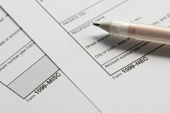 IRS Form 1099-MISC and Form 1099-NEC side by side with a pen