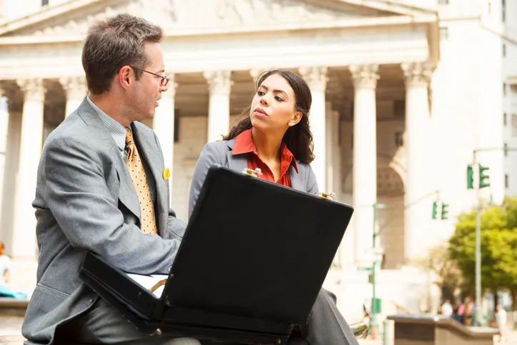A businessman and businesswoman talking outside a courthouse